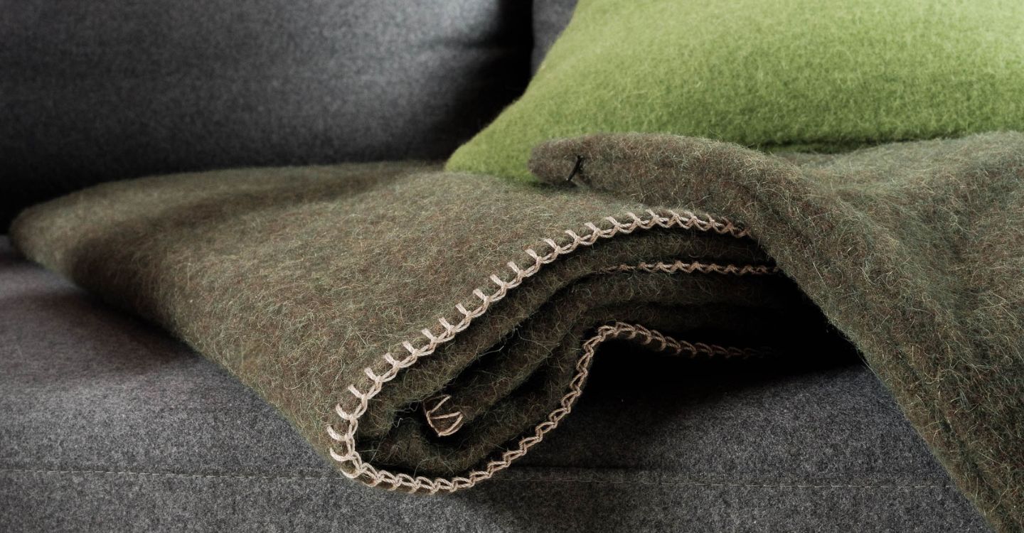 Detailaufnahme gefalteter Wolldecken in Grün und Braun