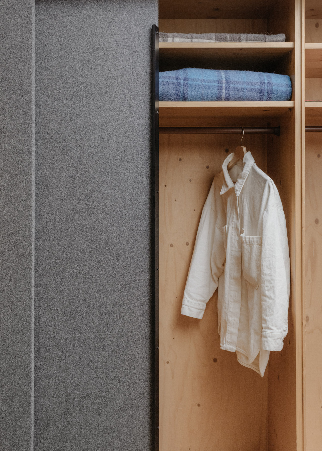 Kleiderschrank mit grauer stoffbezogener Schiebetür
