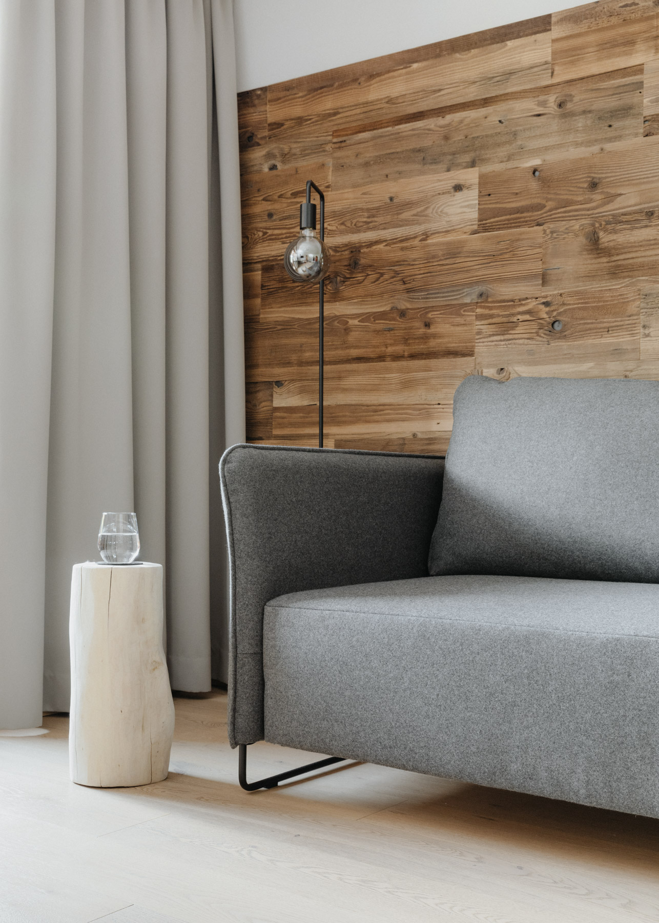 Graues Sofa vor einer Holzwand mit dekorativer Beleuchtung