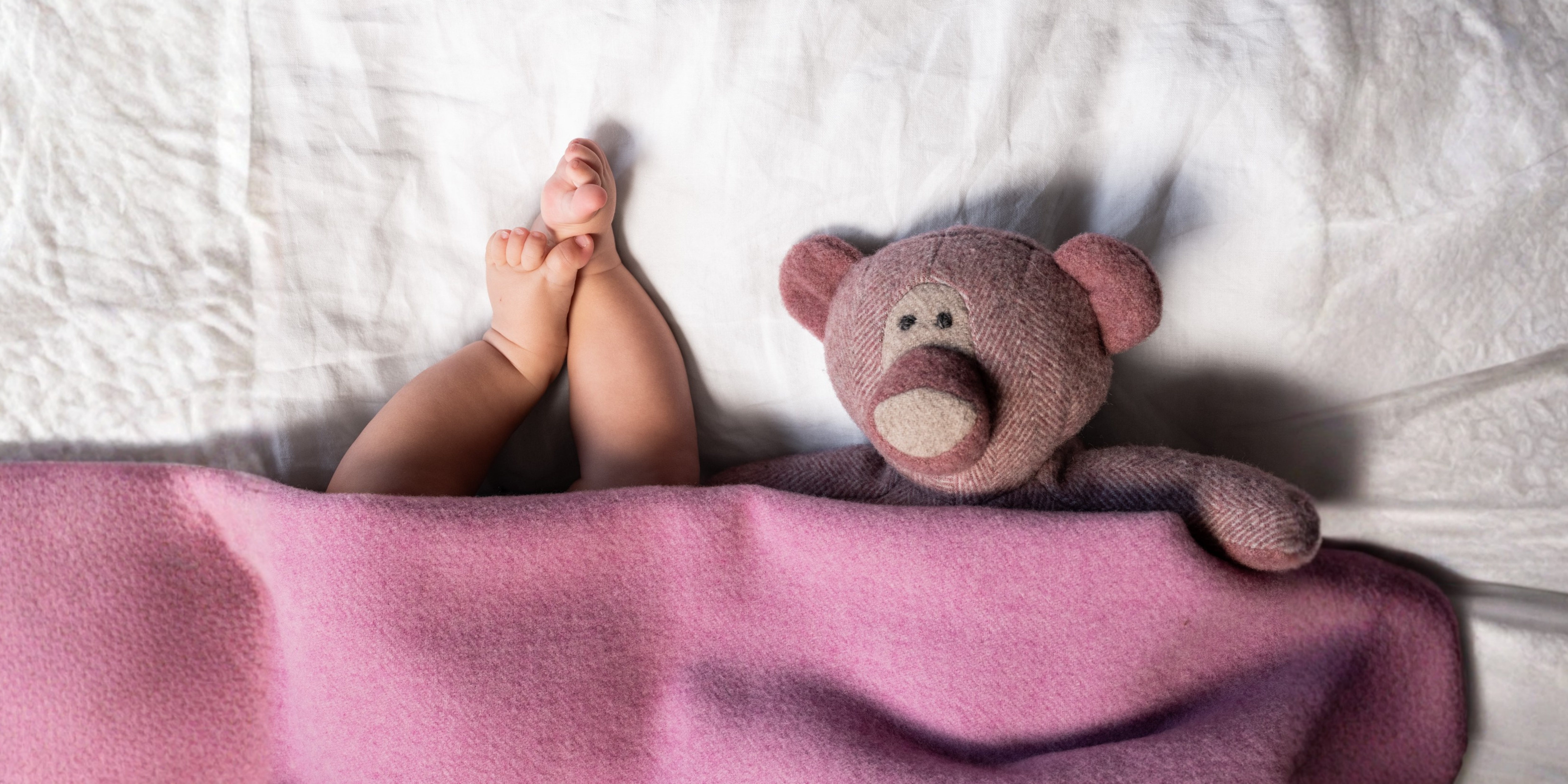 Baby unter weicher Wolldecke mit Teddybär – nachhaltige Babydecke aus Wolle für natürliche Wärme und Geborgenheit