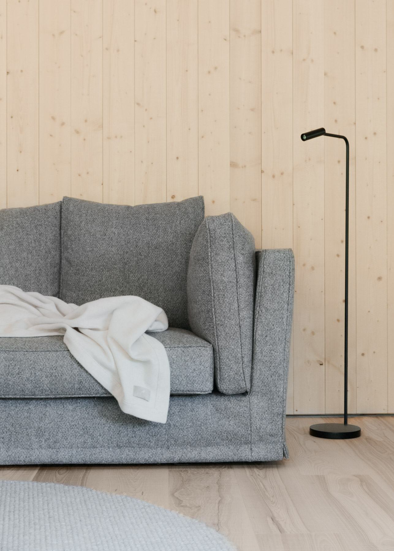 Detailansicht eines grauen Sofas mit Kissen und Decke