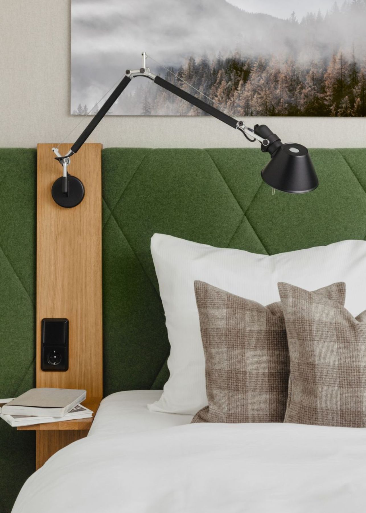 Schlafzimmer mit grüner Wandverkleidung aus Bezugsstoff und gemusterten Kissen